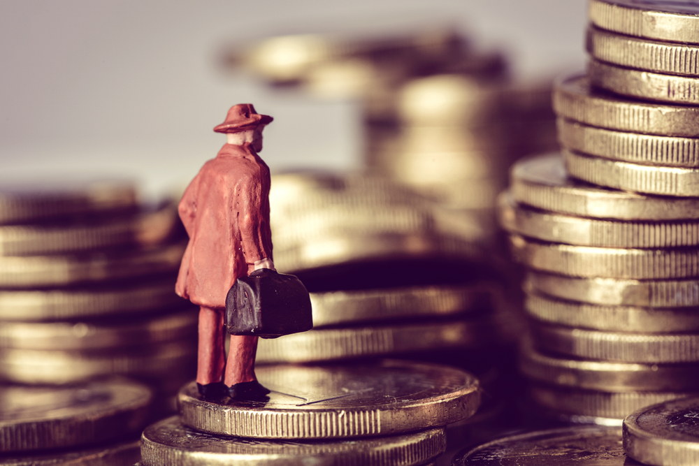 A stack of coins with a figurine standing by it